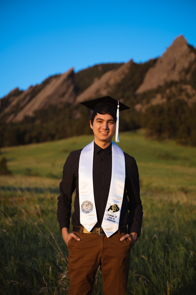 medium shot of Male college graduation photo posing in front of senic mountian background