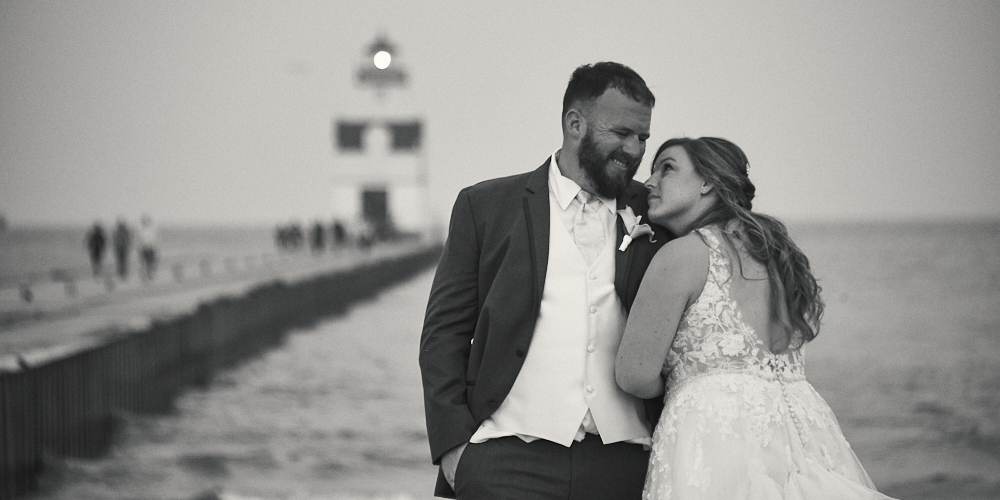 Bride and Groom posing in front of lighthouse in black and white
