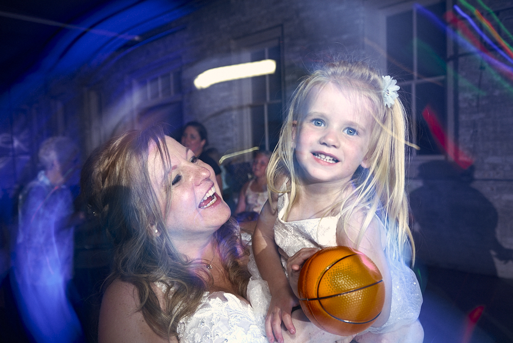 Bride holding girl with blurry lights around them