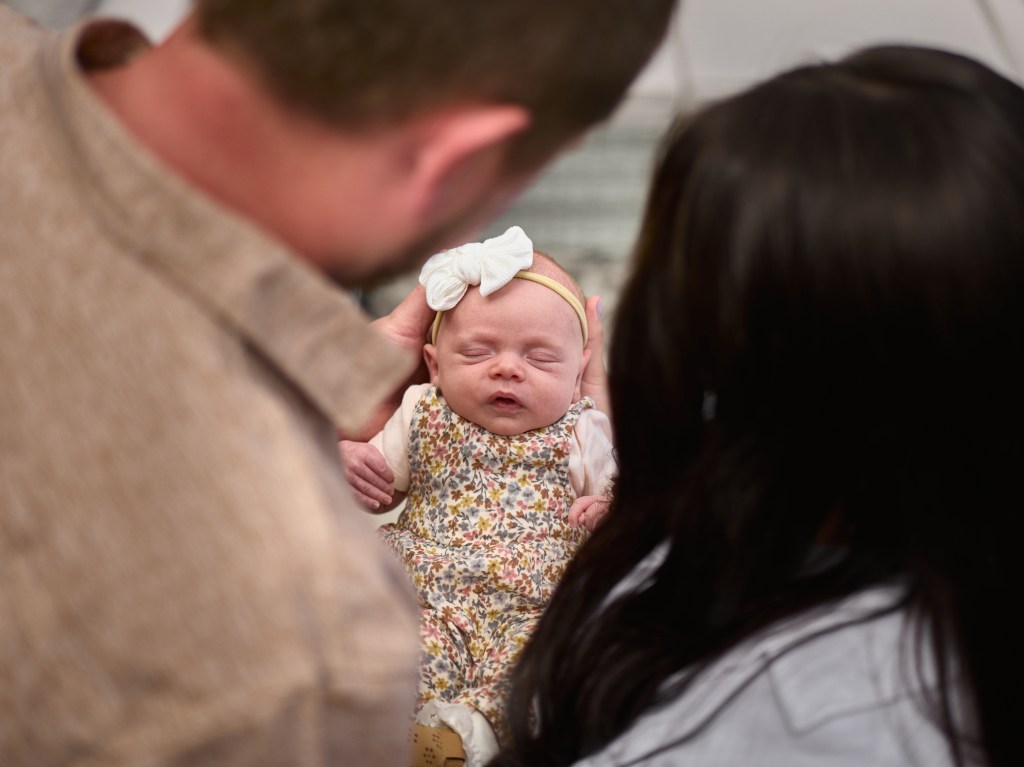 out of focus Mother and father hold newborn between them in focus