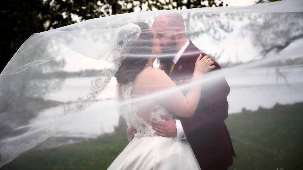 Bride and groom kissing under veil
