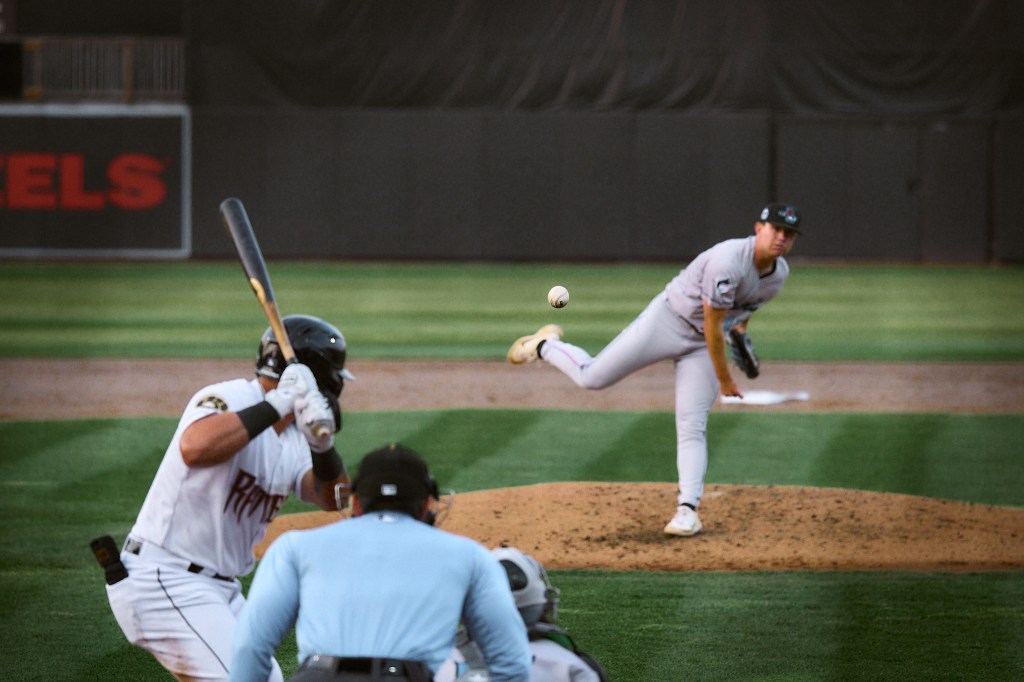 Sports photo of a baseball in focus after pitcher threw it and the batter gets ready to hit it.